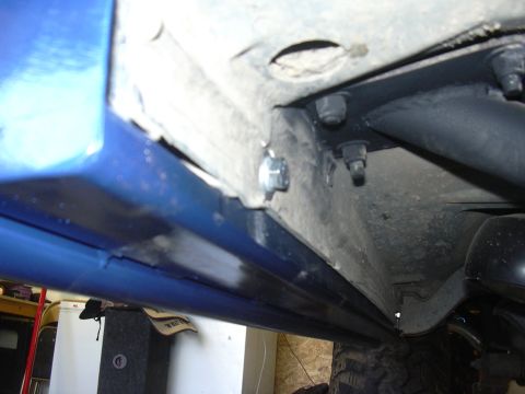 1991 Ford Bronco - The underside of a vehicle, focusing on the rock sliders and their attachment points to the chassis.
