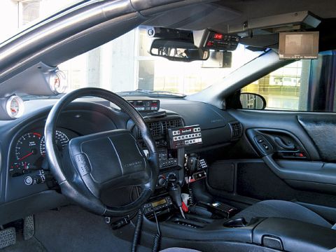 2000 Ford Crown Victoria - The interior of a car is equipped with a police scanner, radio, and a small monitor, suggesting it may be a police or emergency vehicle.