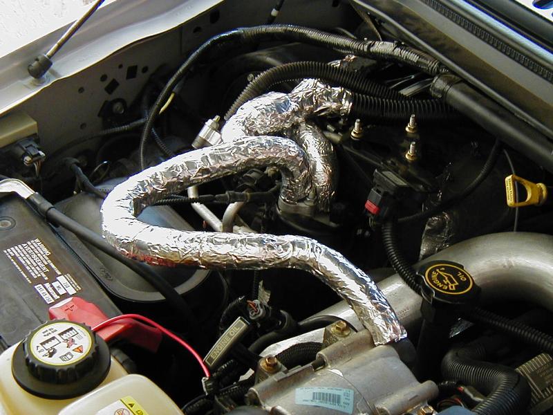Engine bay with foil-wrapped heat-shielded hoses and black oil cap