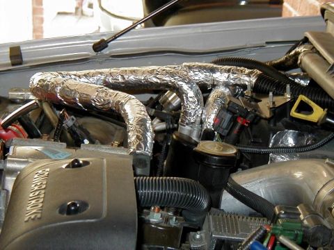 2002 Ford Excursion - Close-up of an engine bay showing modified exhaust components wrapped in heat-resistant material.