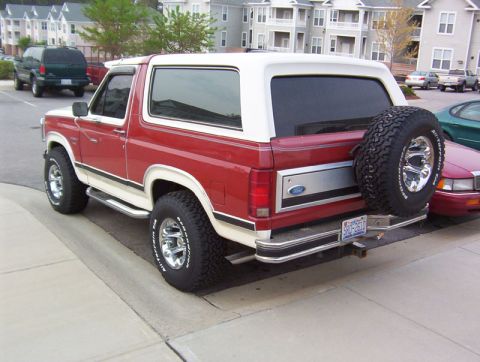 1986 Ford Bronco - This 1986 Ford Bronco features a two-tone red and white paint scheme and a rear-mounted spare tire.