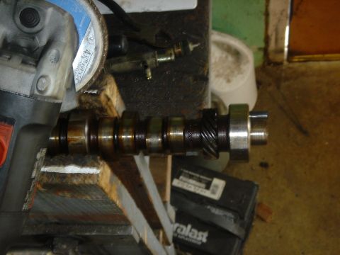 1986 Ford Mustang - A camshaft is being worked on, with an angle grinder and other tools in the background.
