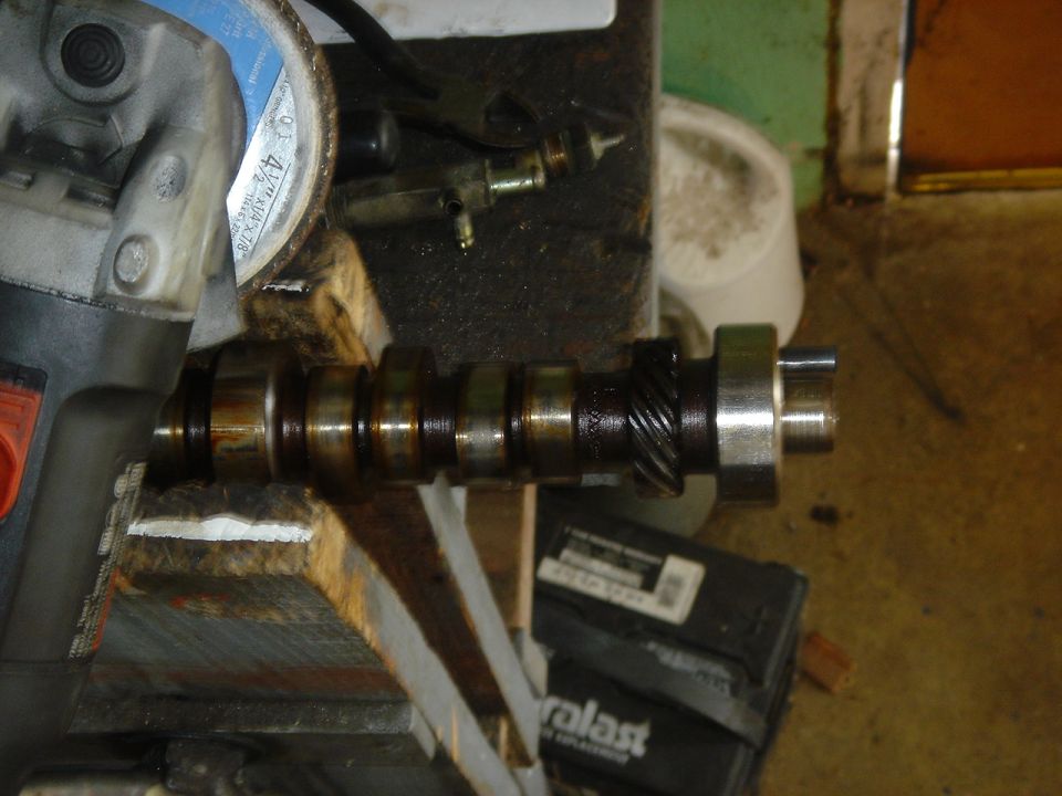Camshaft held in a vise with an angle grinder nearby