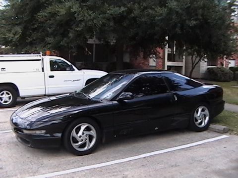 1993 Ford Probe - A black 1993 Ford Probe is parked next to a white truck.
