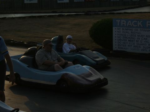 1998 Ford Taurus - Go-karts race on a track with rules posted on a sign.