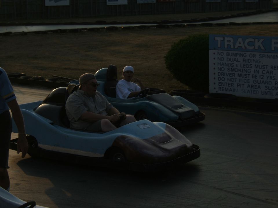 Two go-karts on a track, one with a man driving, the other with a child