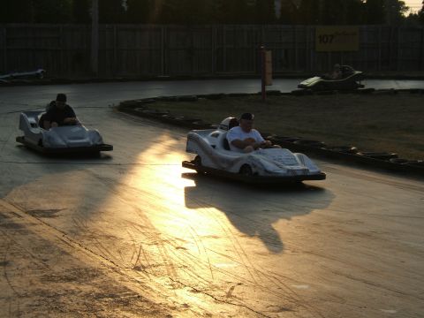 1998 Ford Taurus - Go-karts race on a track during golden hour, with long shadows cast across the pavement.