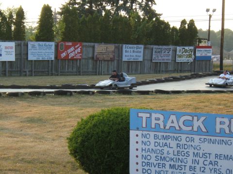 1998 Ford Taurus - Two go-karts race on a track, with a sign detailing track rules in the foreground.