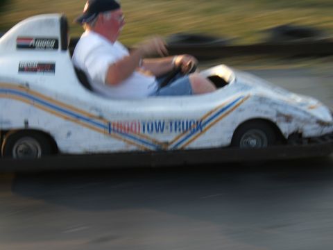 1998 Ford Taurus - Man drives a go-kart labeled 'TURBO TOW-TRUCK' on a track.