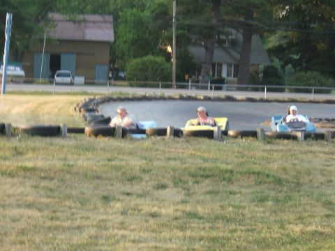 1998 Ford Taurus - Three go-karts are on a race track, with drivers wearing hats and helmets.