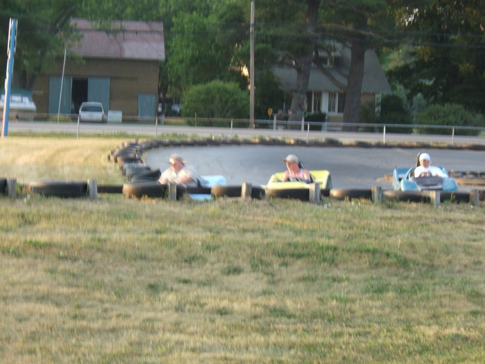People in go-karts racing on a track with tire barriers
