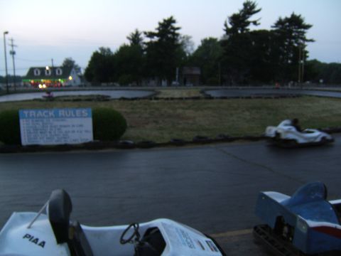 1998 Ford Taurus - Go-karts race on a wet track as dusk settles, with a rules sign visible.