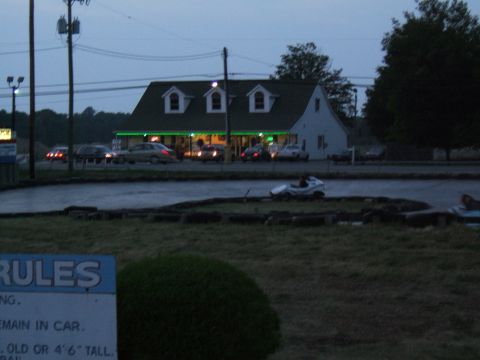 1998 Ford Taurus - Evening scene at a go-kart track with multiple vehicles and a building.