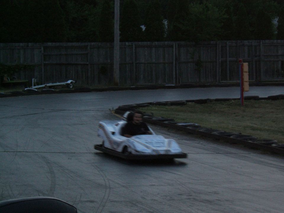 Go-kart with driver on a paved track, fence in background