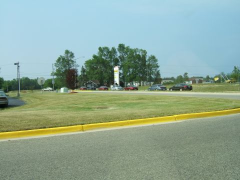 1998 Ford Taurus - A collection of vehicles are visible on a road with a yellow curb and a bright blue sky overhead.