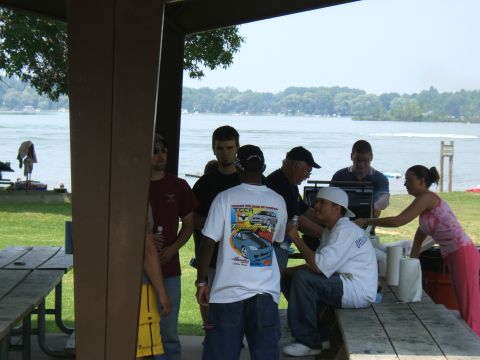 1998 Ford Taurus - A group of people are gathered outdoors near a body of water, with one person in the foreground wearing a t-shirt car images.