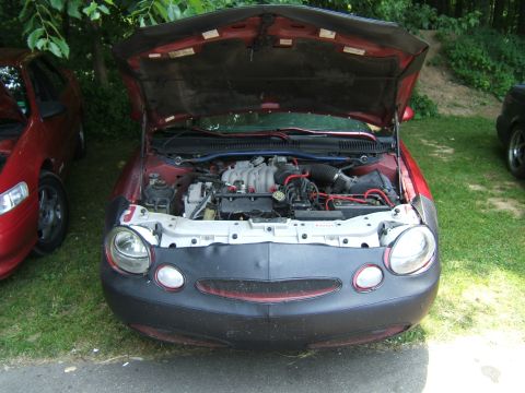 1998 Ford Taurus - Front view of a 1998 Ford Taurus with its hood open, revealing the engine compartment.