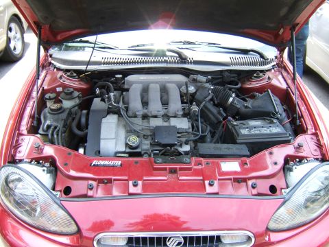 1998 Ford Taurus - The engine bay of a red sedan is open, revealing the V6 engine and various components under the hood.