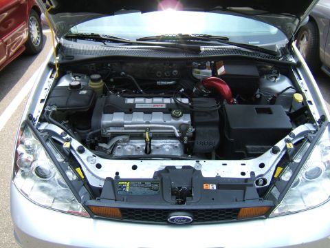 1998 Ford Taurus - The engine bay of a silver Ford Focus SVT is visible, with a red intake pipe and the Ford logo on the grille.