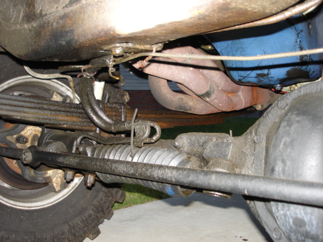 Undercarriage view of a 1978 Ford F-250 showing leaf springs, steering rack, and exhaust manifold
