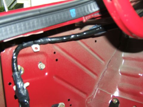 1998 Ford Taurus - Wiring harness routed along the interior body panel of a red vehicle.