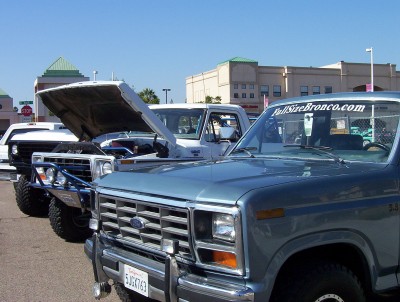 1995 Ford Bronco - Line of Ford trucks and Broncos at a car show, one with hood open.
