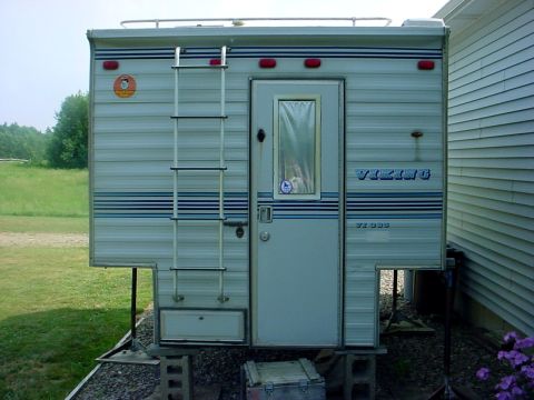 1973 Ford Ranchero - This Viking truck camper is parked next to a house and supported by concrete blocks.