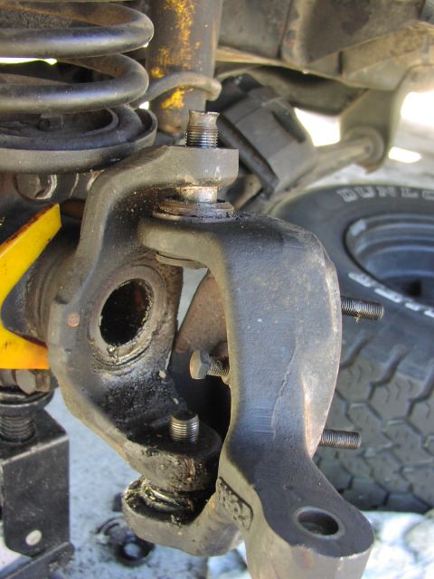 1979 Ford Bronco - Close-up of a front steering knuckle with the hub removed, showing the threaded upper and lower ball joint studs protruding through the yok…