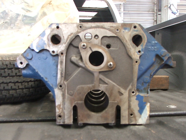 Engine block with blue paint, sitting on a surface next to a tire