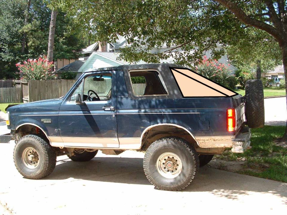 Lifted blue and tan Ford Bronco with black soft top, side view in driveway