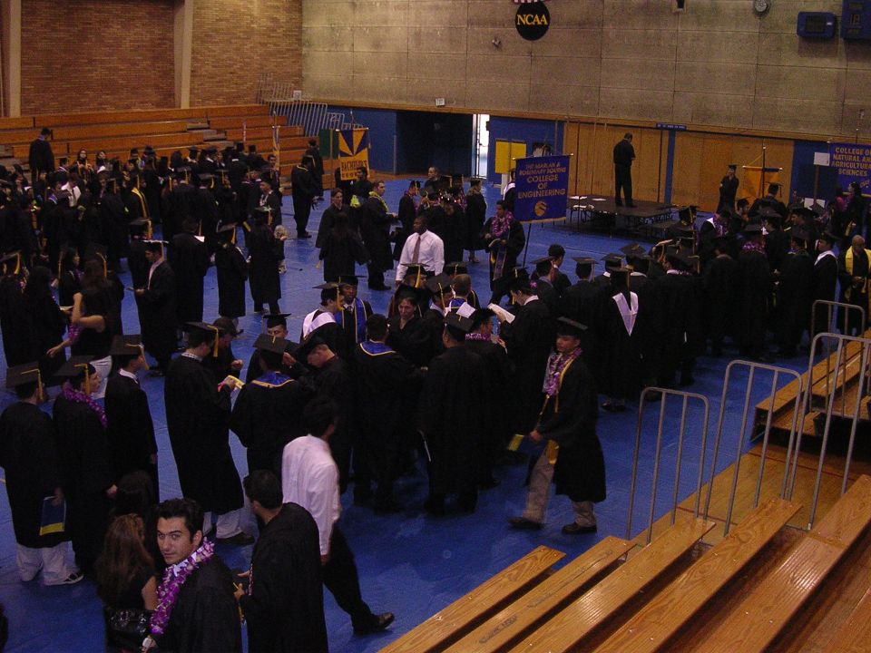 Graduation ceremony with students in caps and gowns gathered in a gymnasium