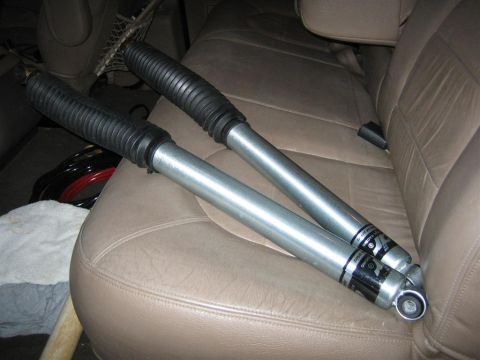 1994 Ford Bronco - A pair of shock absorbers are placed on the back seat of a vehicle.