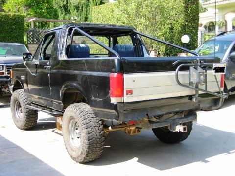 1985 Ford Bronco - This black 1985 Ford Bronco features a custom roll cage and large off-road tires, suggesting it's modified for use.