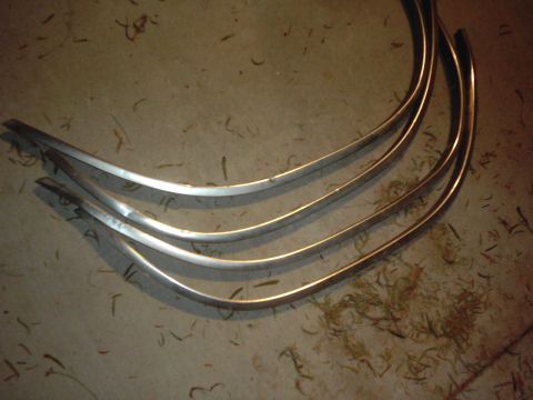 1978 Ford Bronco - Several curved chrome trim pieces are shown on a floor, possibly for a vehicle restoration project.