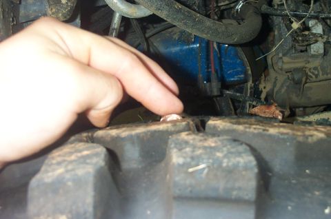 1987 Ford Bronco - A nail is lodged in the tread of a tire, with a hand indicating its presence.