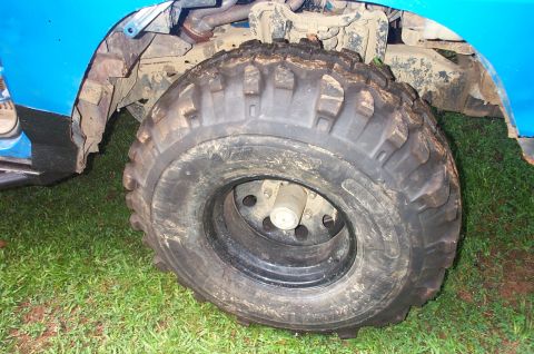 1987 Ford Bronco - Close-up of a vehicle's front wheel and fender, showing off-road tires and muddy undercarriage.