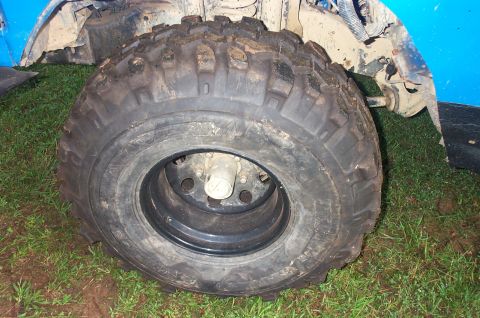 1987 Ford Bronco - This photo shows a close-up of a off-road tire and wheel assembly, with the vehicle's blue bodywork in the background.