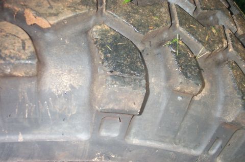 1987 Ford Bronco - A close-up view of a tire tread shows mud and grass embedded in the deep grooves.