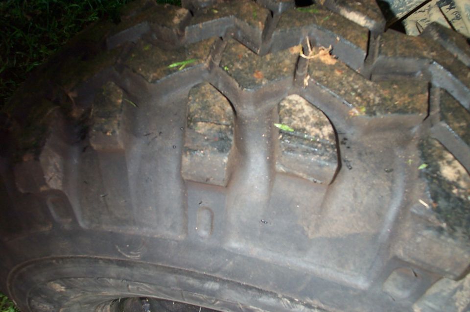 Close-up of a muddy tire tread with visible SuperMotors logo