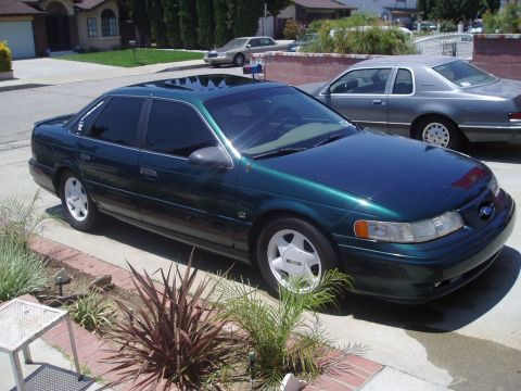 1993 Ford Taurus - A dark green sedan is parked in a suburban driveway with a second car visible behind it.