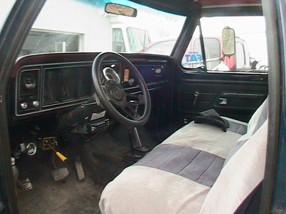 View of a truck's interior, showing the dashboard, steering wheel, and seats. A "SUPERMOTORS" watermark is visible