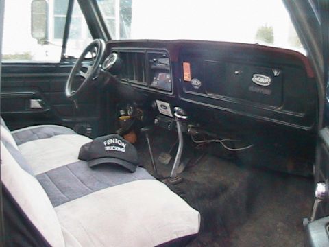 1977 Ford F-250 - The interior of a truck cab features a dashboard with various gauges and a steering wheel, along with a hat on the seat.