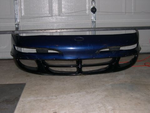 1997 Ford Probe - A blue car bumper with a black grille is shown in front of a garage door.