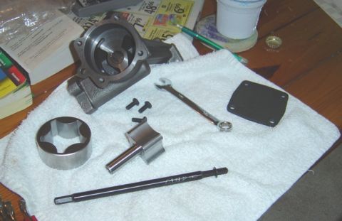 1986 Ford Bronco - Disassembled oil pump components and tools are arranged on a white towel on a wooden surface.
