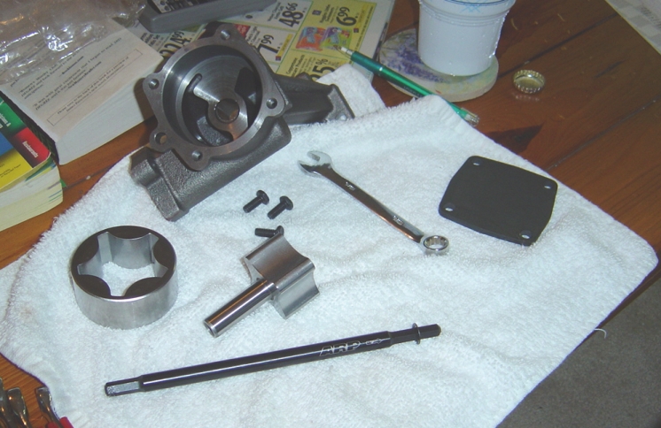 Disassembled pump on a white towel, housing, rotor, shaft, cover plate, bolts and a wrench.
