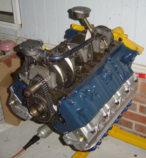 1986 Ford Bronco - A V8 engine, painted blue and silver, is mounted on a yellow engine stand, revealing its internal components.