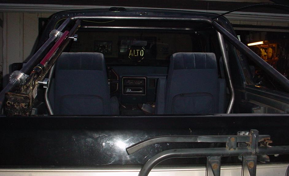 Interior view of vehicle with roll cage and dark blue seats. 'ALTO' visible on rear window