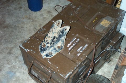 1995 Ford Bronco - Weathered flat steel bracket drilled with multiple holes, in worn black paint, resting on an olive-drab military ammunition crate stenciled…