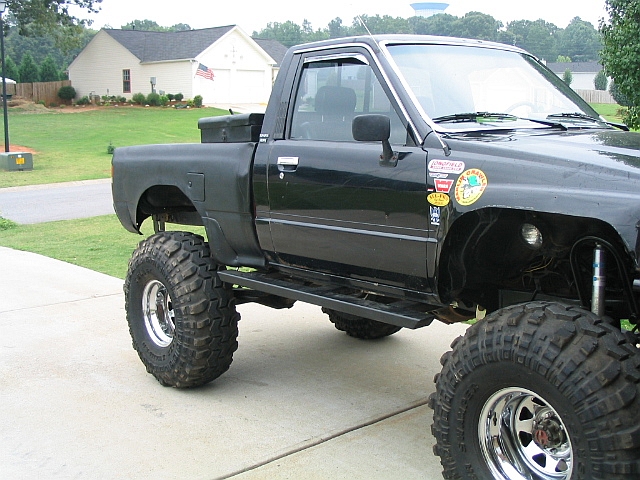 Black lifted pickup truck with off-road tires and stickers on the fender