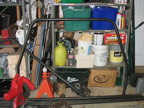 1986 Ford F-150 - Garage scene with a roll cage, jack stands, and various storage bins and containers.